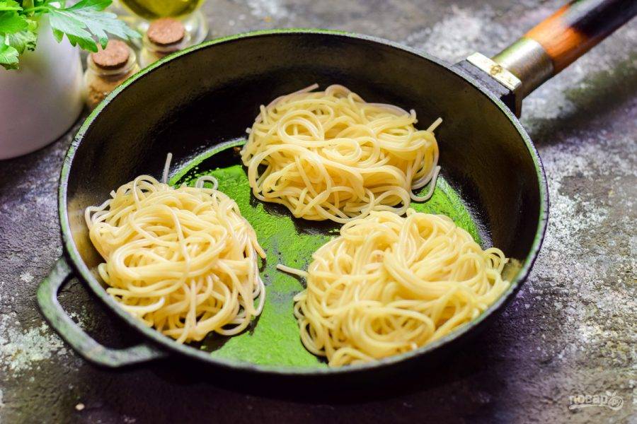 Спагетти отварите до полуготовности. Переложите спагетти в виде гнезд в сковороду.