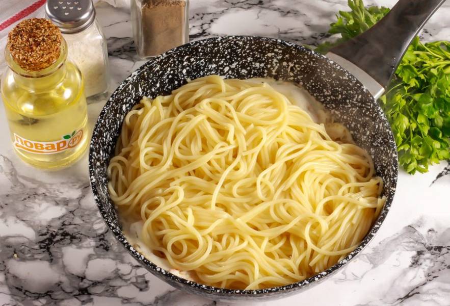 Выложите спагетти и перемешайте. Прогрейте примерно 2-3 минуты и выключите нагрев. Так как сейчас магазинная сметана может расслоиться, поэтому отдельно ее в соусе прогревать не нужно — сразу добавляйте пасту.