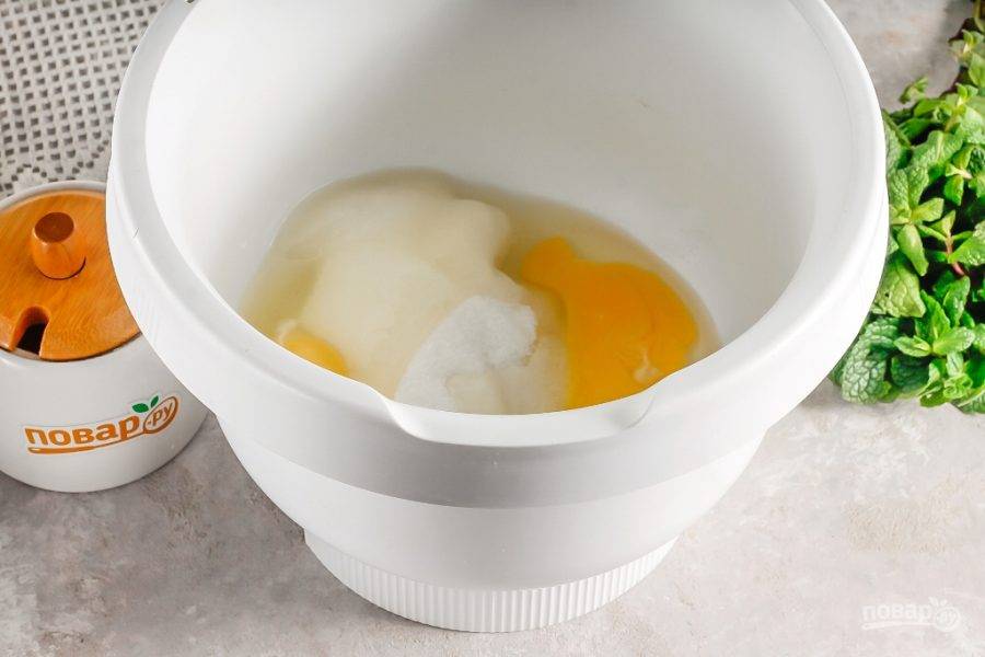Куриные яйца вбейте в емкость кухонного комбайна или миксера, всыпьте 140 грамм сахара и щепотку соли. Взбейте примерно 4 минуты на самой высокой скорости техники до пышной пены. Главное — не перевзбейте, иначе масса расслоится.