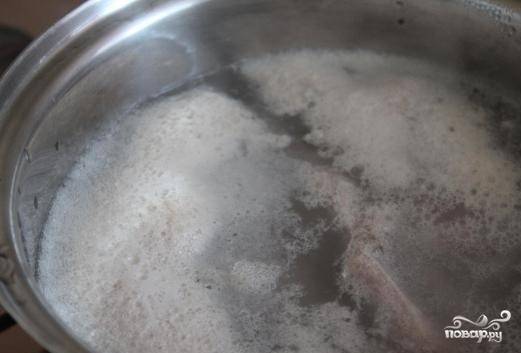 1. Приготовьте бульон из свиных ребрышек. Для этого их необходимо помыть, а затем положить в воду. Когда вода закипит и поднимется пена, слейте. Ребрышки еще раз промойте, переложите в чистую воду и варите до готовности на среднем огне.
