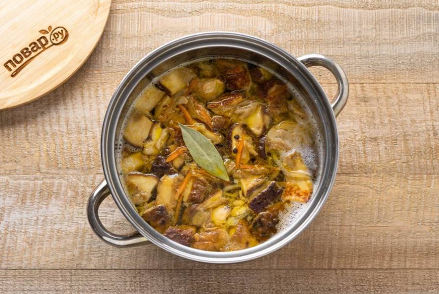 Переложите грибы и овощную зажарку в кастрюлю. Добавьте лавровый лист, перец горошком и посолите суп по вкусу. Варите на среднем огне 15 минут.