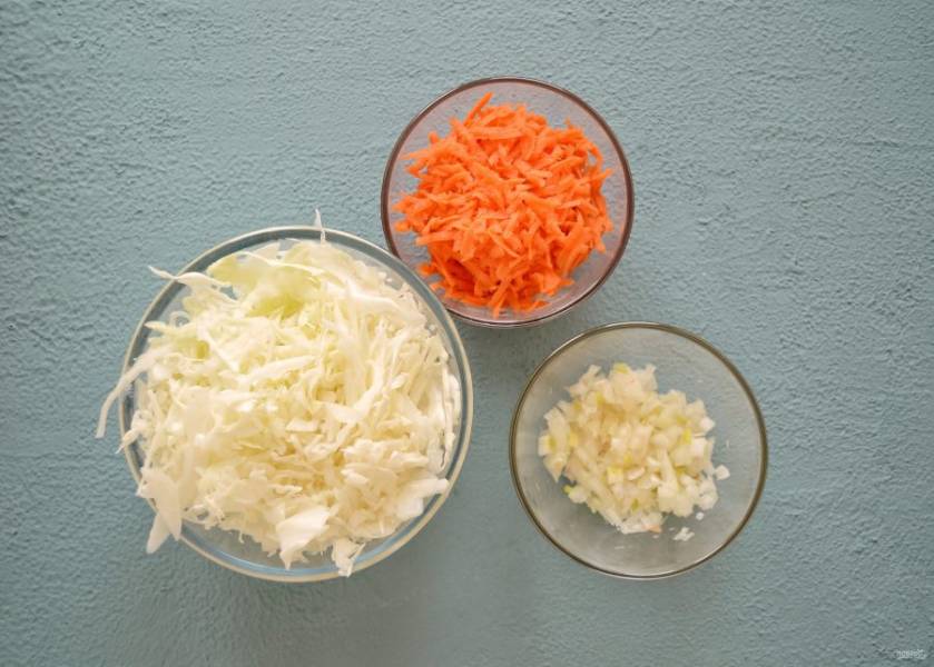 Натрите на крупной тёрке морковь, капусту тонко нашинкуйте, а лук нарежьте мелкими кубиками.  