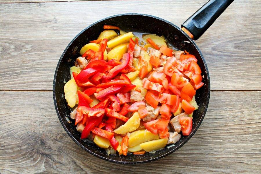 Болгарский перец и помидор порежьте на крупные дольки и выложите в сковороду с рагу. Тушите еще 5-10 минут, до готовности овощей.