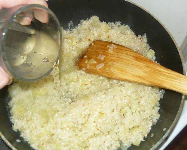 4. Постоянно помешиваем, когда рис прогреется и поменяет немного свой цвет, вливаем вино и воду (примерно, 3 стакана).