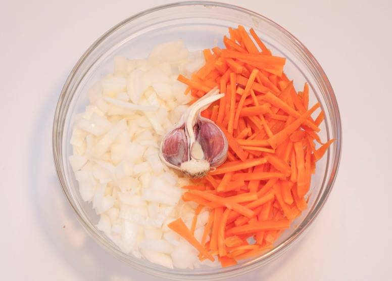 Очищаем и промываем овощи, репчатый лук нарезаем мелко, а морковь режем соломкой. Берем где-то половину головки чеснока, чеснок чистить не нужно, просто снимаем с него верхний слой шелухи.