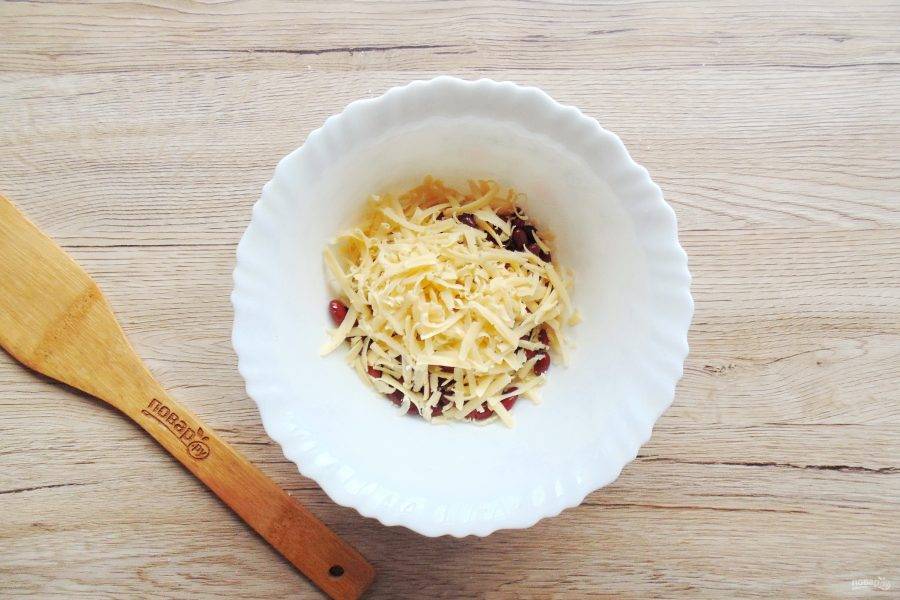 Сыр натрите на тёрке и добавьте в салатник к фасоли.