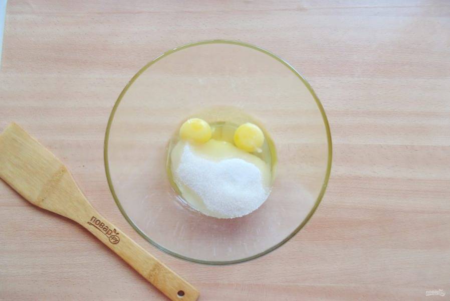 В миску разбейте яйца, и добавьте сахар. Тщательно перемешайте венчиком или миксером.