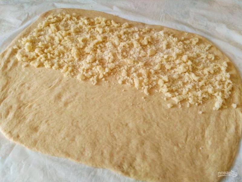 Раскатайте тесто в прямоугольный пласт толщиной 4-5 мм и распределите на одной из его половин часть приготовленной крошки.