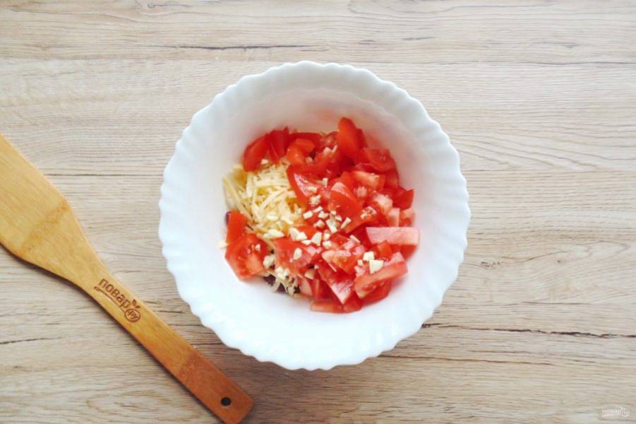 Помидоры вымойте и нарежьте мелко. Чеснок измельчите любым способом. Добавьте в салатник помидоры и чеснок.
