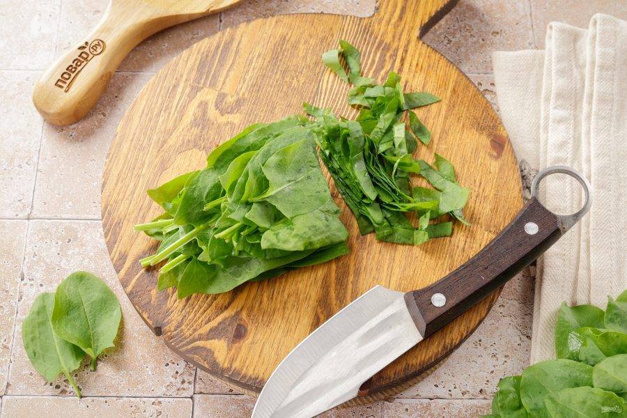 Тем временем щавель сложите стопочкой и нарежьте ножом.