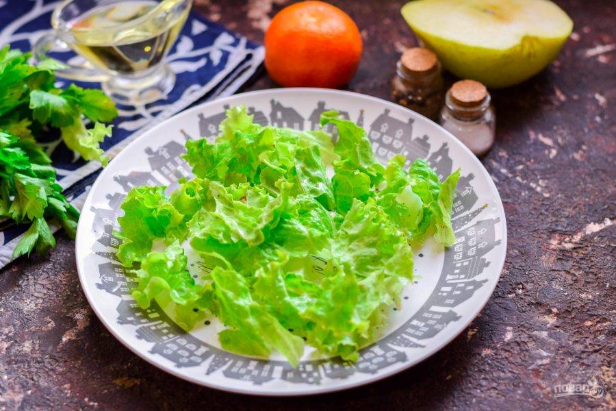 Возьмите тарелку, в которой вы будете готовить салат. Листья салата сполосните и просушите, порвите руками и разложите на тарелку.