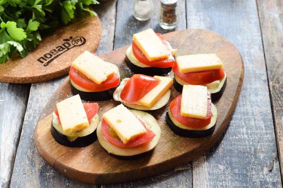 Твердый сыр нарежьте пластинами и выложите поверх помидора.