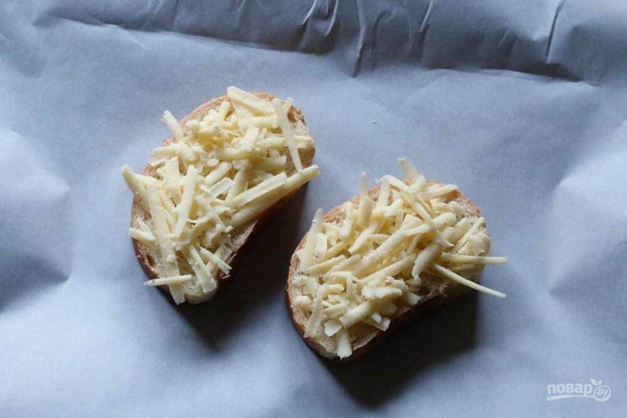 7.	Нарежьте багет и выложите его на противень, застеленный пергаментной бумагой. Натрите сыр и выложите его на кусочки багета.