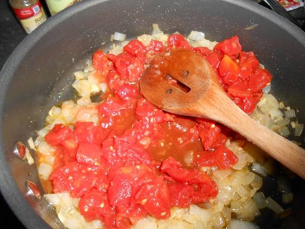 3. Тем временем вымыть, очистить от кожицы и нарезать небольшими кусочками помидоры. Отправить на сковороду к луку. При желании в рецепт приготовления лазаньи с креветками можно использовать и готовый томатный соус. 