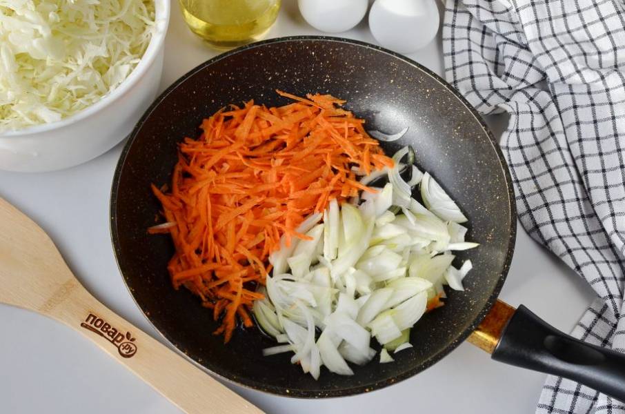 Очистите лук и морковь, натрите морковь на крупной терке, а лук порежьте тонко. Нашинкуйте капусту. Раскалите 2 ложки масла в сковороде, добавьте лук и морковь, жарьте несколько минут.