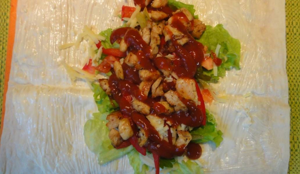 Выложить на лаваш куриное филе, а затем сверху полить кетчупом и посыпать рубленой зеленью. 