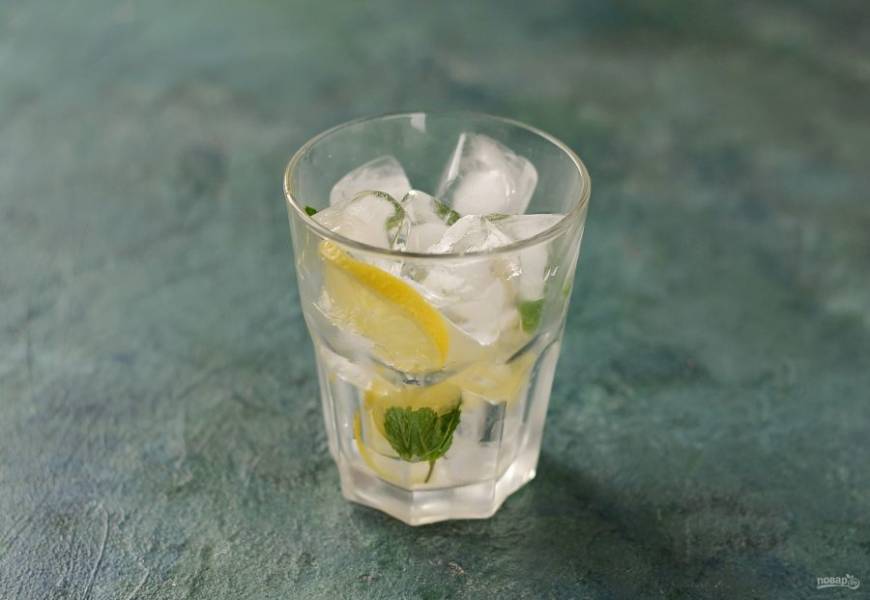 В стакан добавьте лед, лимон и листья мяты.
