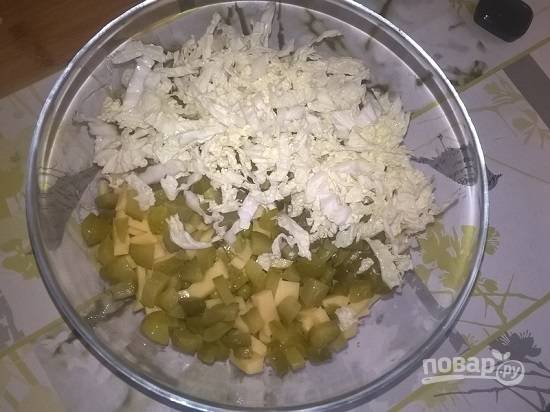 Теперь выложим слой из огурцов, нарезанных мелким кубиком. И последним слоем выкладываем оставшуюся капусту.