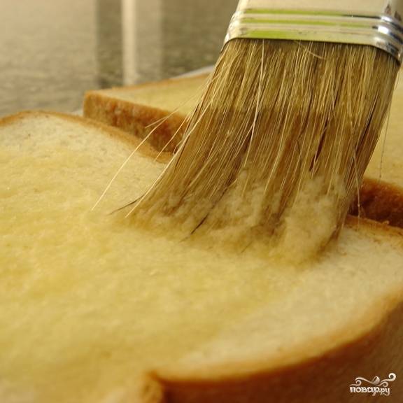 Смазываем каждый ломтик хлеба чесночным маслом.