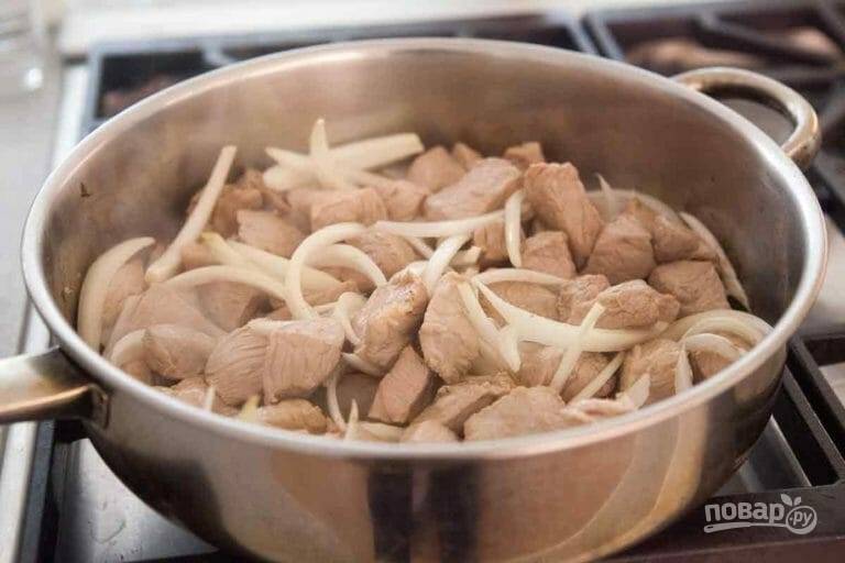 2.	Нарежьте лук полукольцами, измельчите чеснок. Выложите сперва к мясу лук и готовьте еще 5 минут, затем добавьте чеснок и обжаривайте 30-60 секунд.