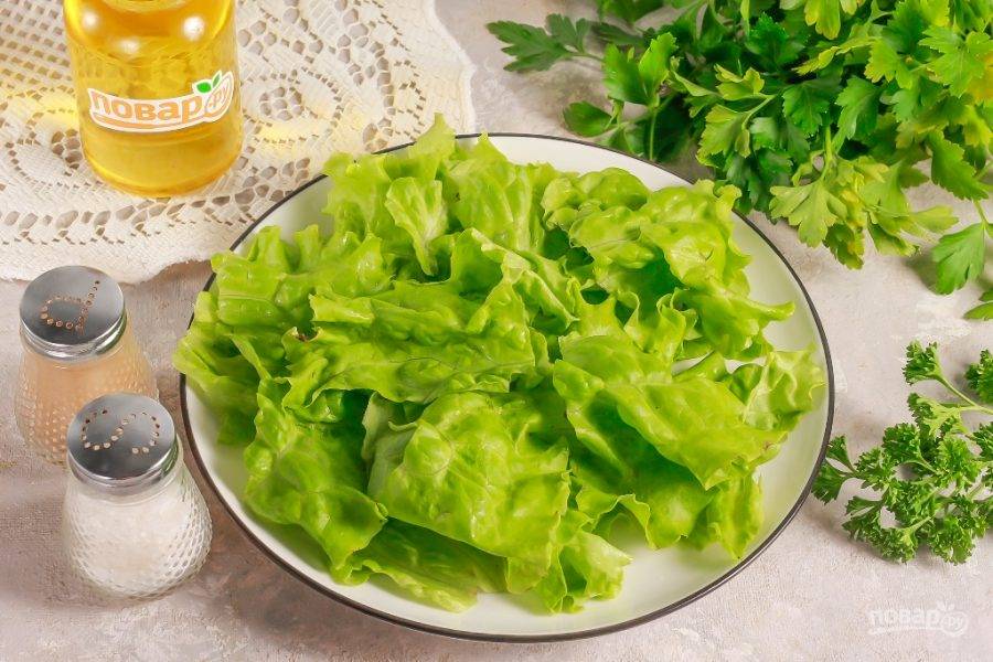 Промойте салатные листья, стряхните лишнюю влагу, срежьте остатки стеблей и нарвите их руками на тарелку или блюдо.