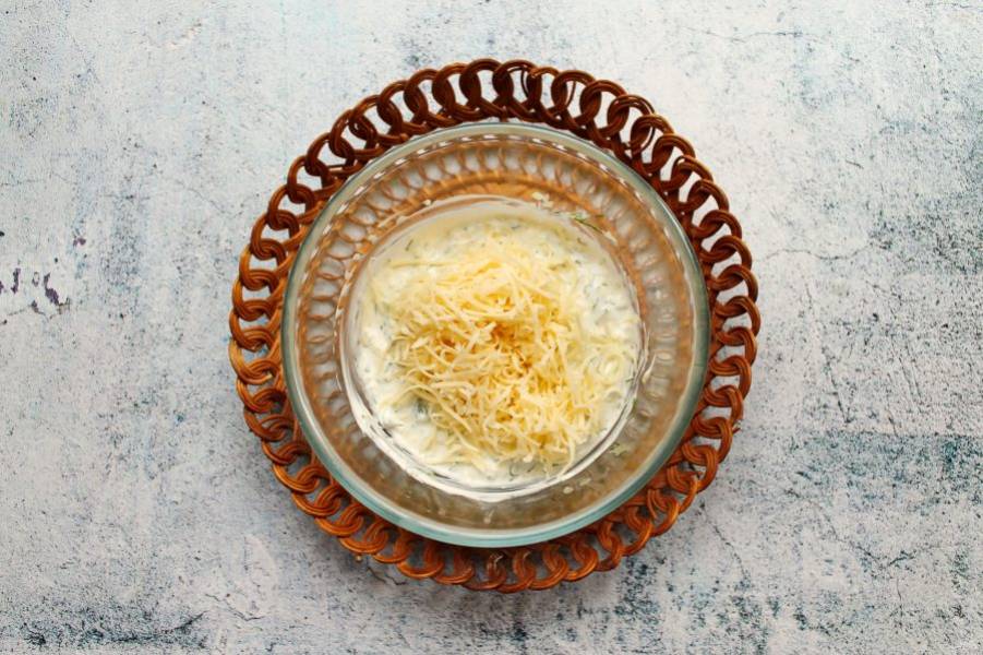Сыр натрите на средней терке и добавьте в миску со сметаной, перемешайте.