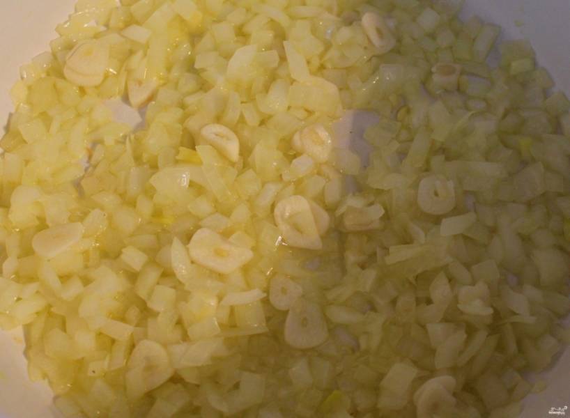 На сковородку налейте две столовые ложки оливкового масла холодного отжима, поставьте на плиту. Разогрейте. Очистите лук и чеснок, мелко их нарежьте. Затем обжарьте на среднем огне на разогретом растительном масле, пока они не начнут источать характерный аромат и не приобретут прозрачность и золотистый оттенок. 