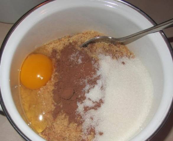 4. В размягченное масло высыпьте образовавшуюся крошку. Добавьте яйцо. Всыпьте какао-порошок и сахар песок. 