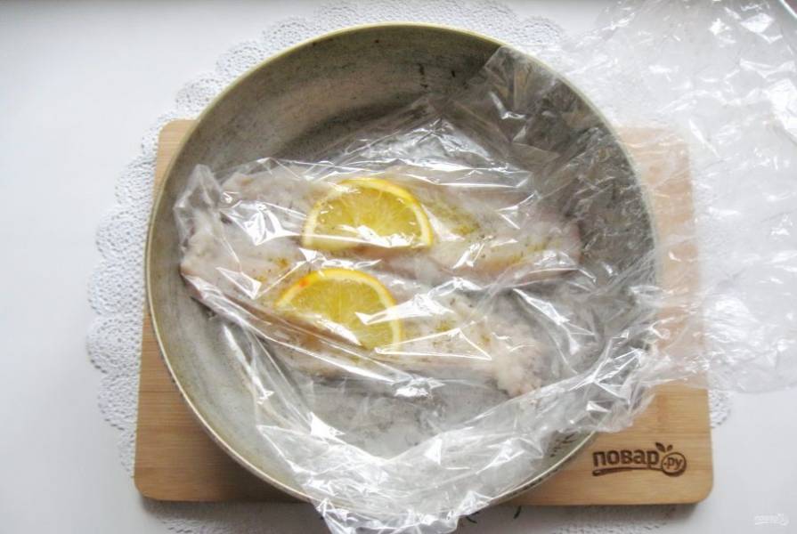 Выложите рыбу в рукав или пакет для запекания. Посолите, посыпьте сушеным розмарином. На каждый пласт минтая добавьте дольку апельсина.