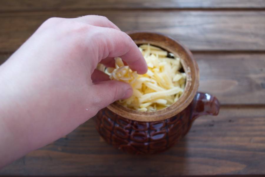 Залейте горшочки бульоном на уровень 1/3 горшка. Натрите на терке твердый сыр. Посыпьте картофель сыром.