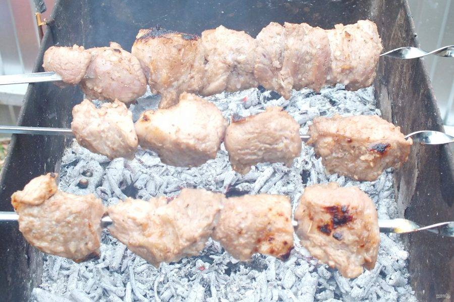 Подготовьте мангал заранее. Перед жаркой шашлыка угли должны быть "седыми". Насадите замаринованное мясо на шампуры, разложите на мангале.