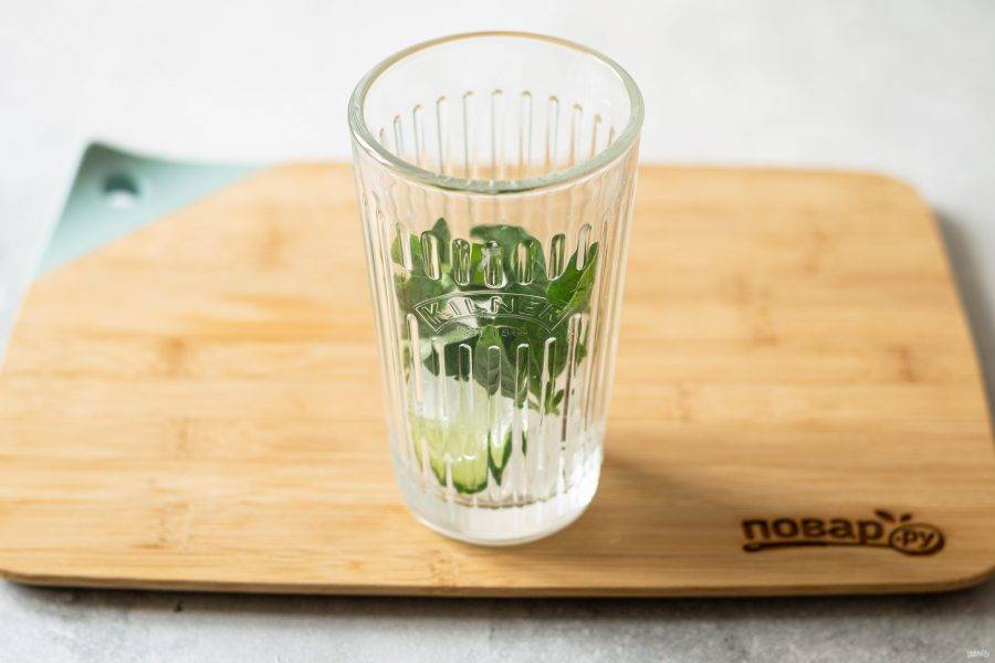 На дно стакана выложите немного льда. Отделите листики орегано от веточки, слегка помните их и переложите в стакан.