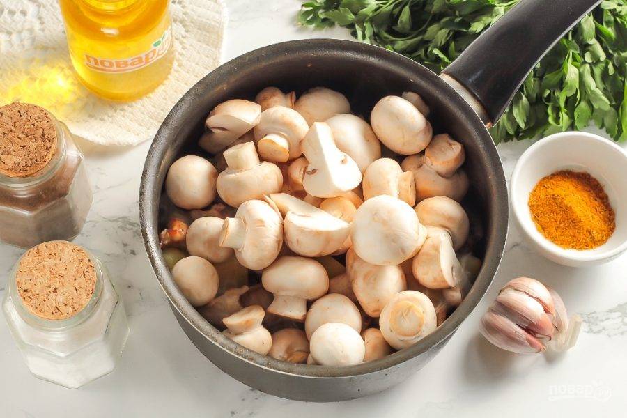 Нарежьте половину очищенного лука полукольцами и добавьте в емкость вместе с шампиньонами. Если грибы крупные, то нарежьте их на четвертинки. Обязательно посолите и перемешайте. Соль вытянет из грибов всю жидкость. Обжаривайте на умеренном нагреве примерно 8-10 минут. Грибы выпустят жидкость и все нарезки в ней пропарятся.