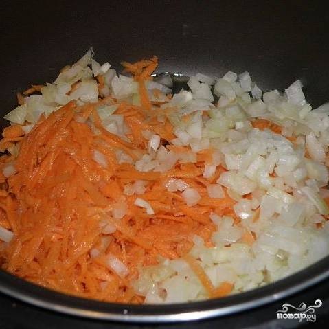В чашу мультиварки налить растительное масло. Добавить подготовленные морковь, лук и чеснок. Выбрать режим "Выпечка", время готовки 20 минут. Обжаривать овощи, помешивая время от времени.