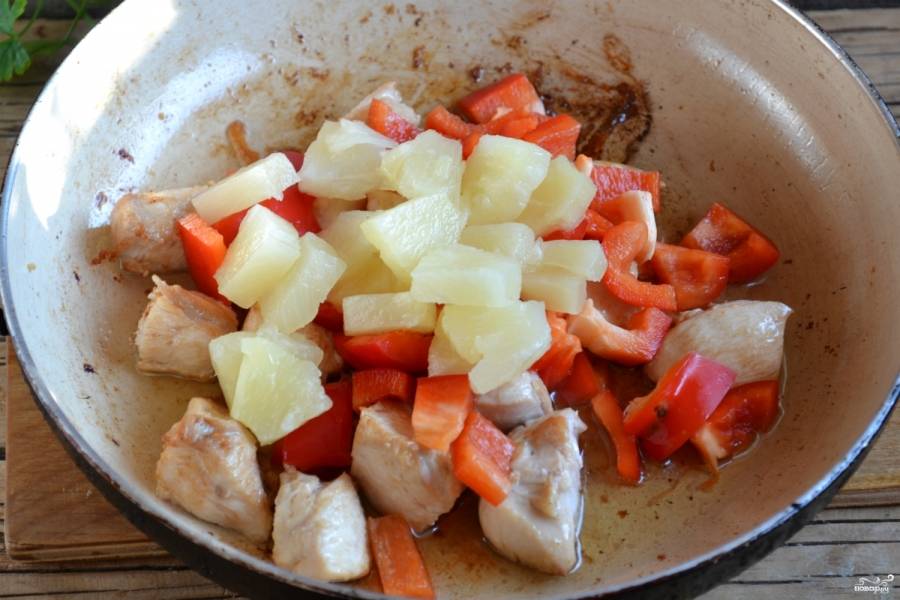Добавьте в сковороду к курице перец и ананасы кусочками, жарьте до мягкости перца.