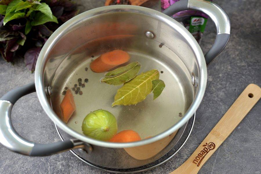 Вскипятите в кастрюле воду, выложите в нее лавровый лист, перец горошком, нарезанную крупными ломтиками морковь и надрезанный крестообразно лук. Воду хорошенько посолите. 
