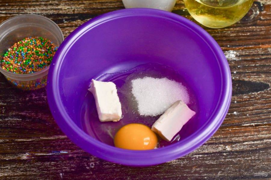 В миску вбейте яйцо, добавьте сахар и выложите сливочное масло.