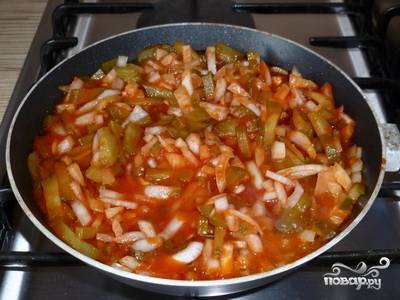 Выкладываем лук и огурцы на глубокую сковороду, добавляем томатную пасту и подсолнечное масло. Накрываем крышкой и тушим 15 минут. После чего солим и тщательно перемешиваем. 