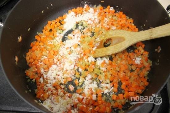 5. Нарежьте морковь маленькими кубиками и отправьте вместе с чесноком к луку обжариваться до мягкости моркови. Влейте куриный бульон, молоко и воду.