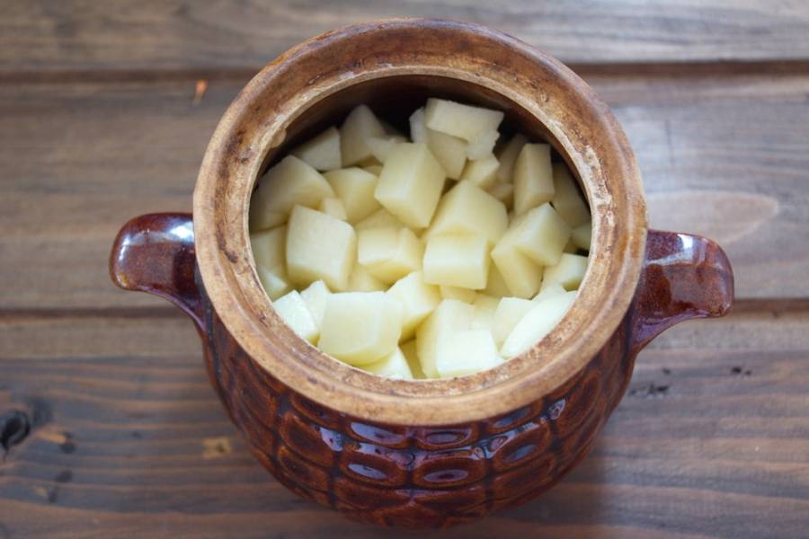 Картофель нарезать кубиком, выложить в горшочек.