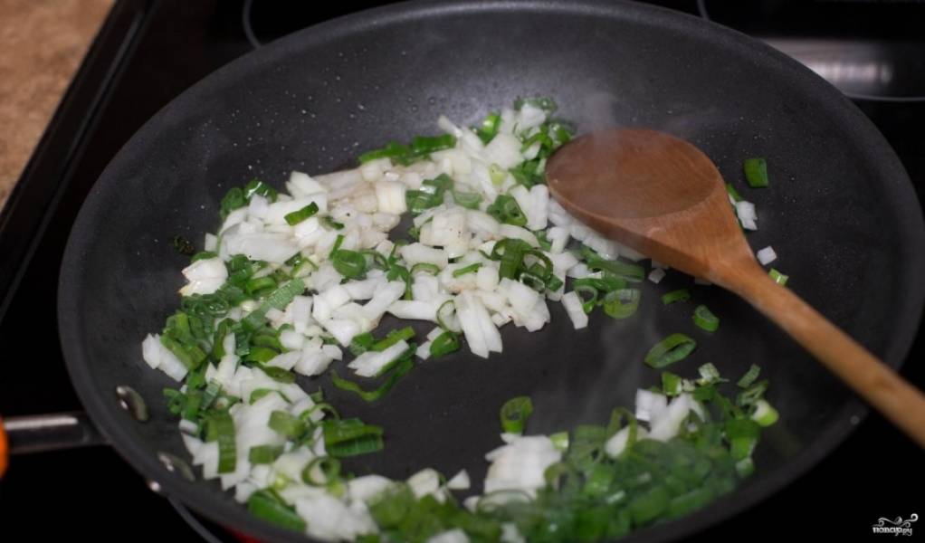 Шаг 5.
Возьмите вторую половинку луковицы, нарежьте ее мелкими кубиками, то же самое проделайте и с зеленым луком. Высыпьте лук на ту сковороду, где жарили тефтели.
