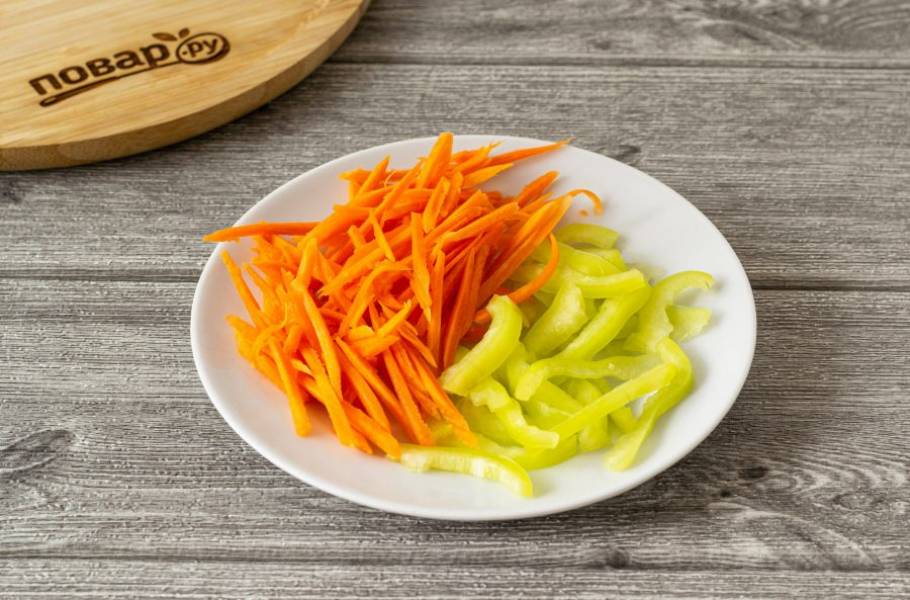 Морковь очистите и натрите на терке для корейской моркови. У болгарского перца удалите семена, перегородки и хвостик, нарежьте на тонкие полосы.