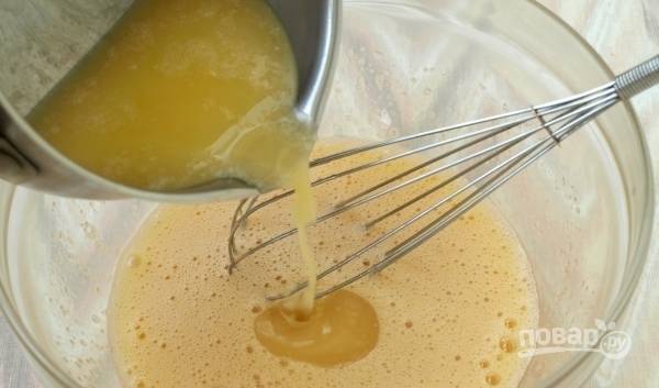 Сливочное масло растопите на водяной бане или в микроволновке. Дайте ему остыть, затем введите его тонкой струйкой к яйцам с сахаром, не переставая их взбивать. 