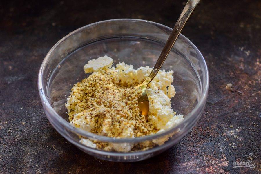 Грецкие орехи измельчите в чаше блендера, после добавьте ореховую крошку в миску с творогом.