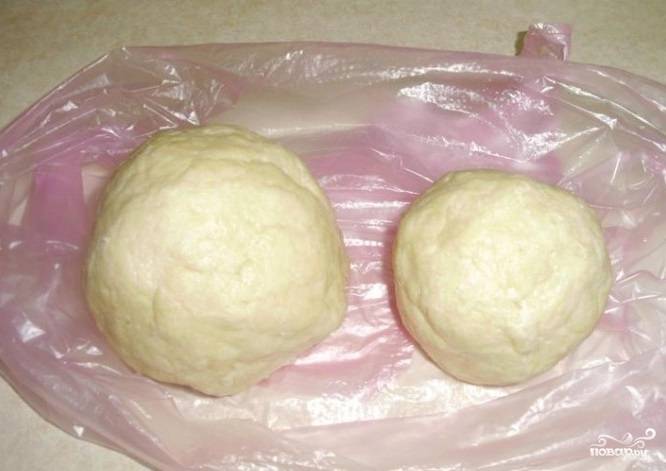 Влейте холодную воду, замесите тесто. Сделайте из него два шара: один больше, а другой меньше. Отправьте их в холодильник под пищевой плёнкой на час.