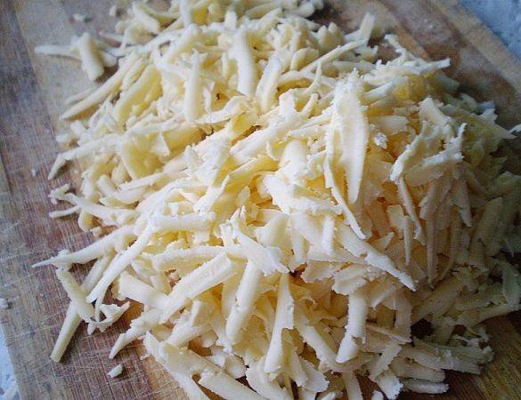 Следующий слой - сырный. Натираем сыр на терке, выкладываем на ветчину и смазываем.