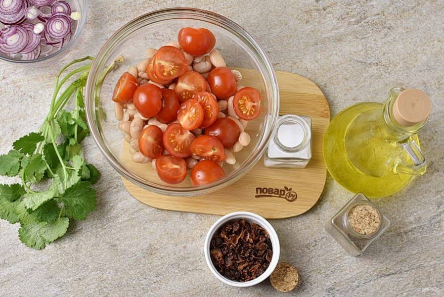В салатную миску выложите хорошо просушенную от заливки фасоль, добавьте помидоры черри, нарезанные половинками.