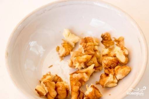 9. Ядра орехов подсушите на сковородке. Выложите часть орехов на одну половину коржа.
