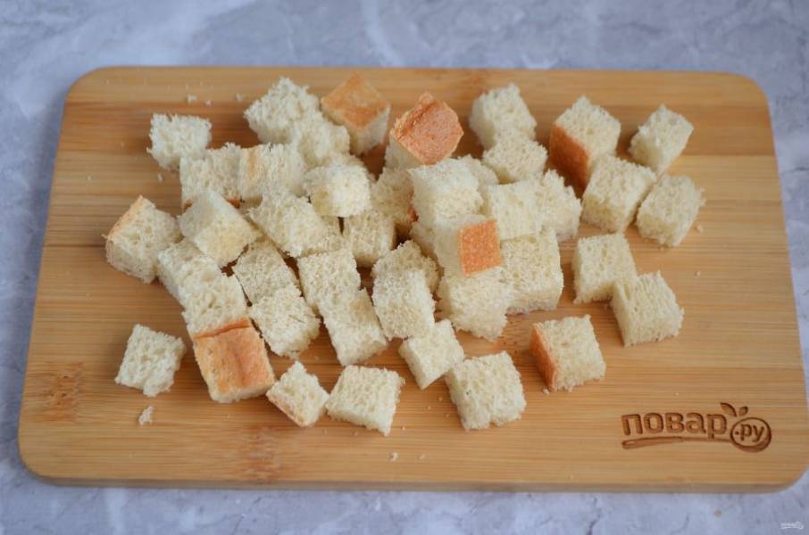 1. Для салата сделайте сухарики. Для этого вчерашний хлеб порежьте кубиками.