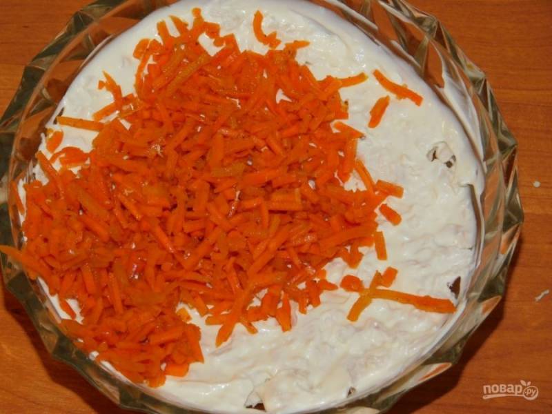 Морковь по-корейски мелко нарежьте и выложите вторым слоем. Также смажьте майонезом.